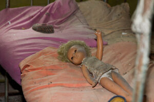 Eine verlassene schmutzige Puppe in einem verlassenen zerstörten Ort in der Ukraine